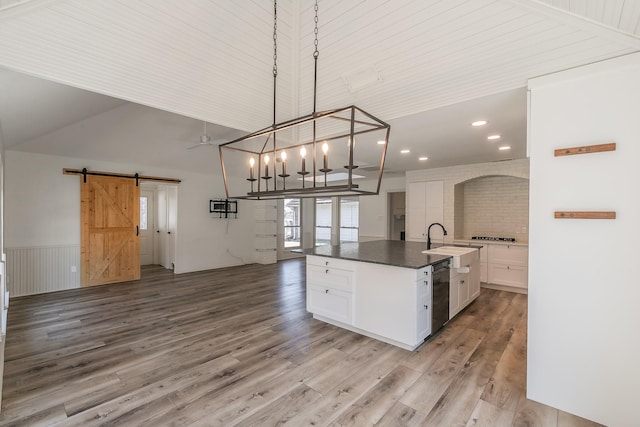 kitchen featuring pendant lighting, an island with sink, black dishwasher, white cabinets, and a barn door