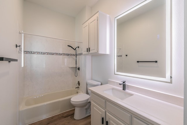 full bathroom featuring vanity, hardwood / wood-style floors, tiled shower / bath combo, and toilet