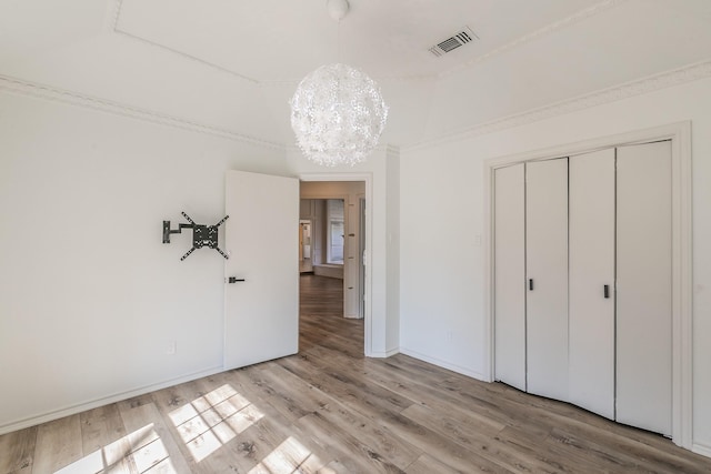 unfurnished bedroom with an inviting chandelier, a closet, and light hardwood / wood-style flooring