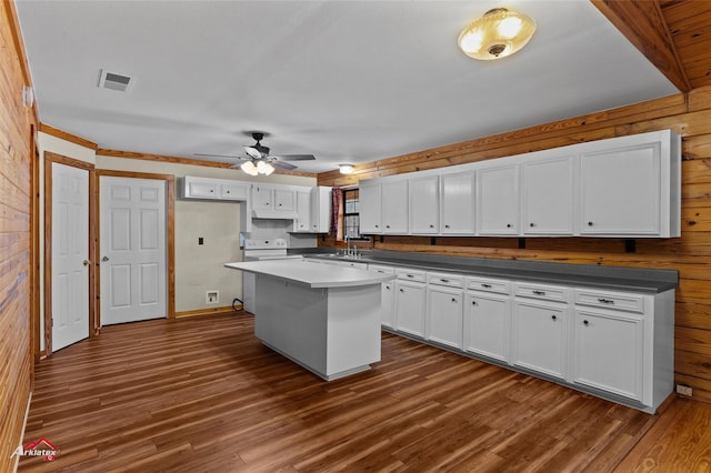 kitchen featuring wood walls, a center island, dark hardwood / wood-style floors, white range with electric cooktop, and white cabinets