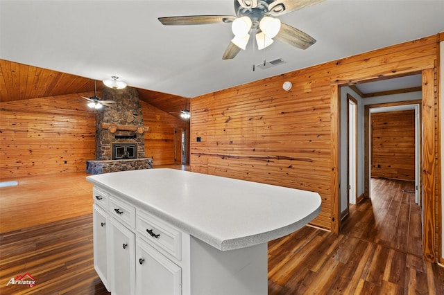 kitchen with white cabinetry, a center island, wooden walls, dark hardwood / wood-style flooring, and ceiling fan