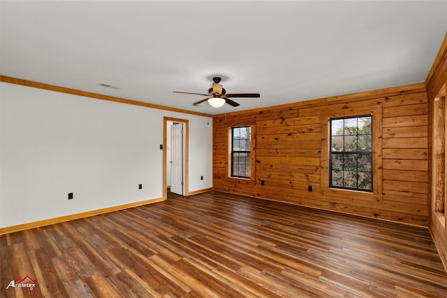 empty room featuring hardwood / wood-style floors, ornamental molding, ceiling fan, and wood walls