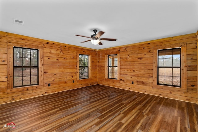 unfurnished room featuring ceiling fan, wood-type flooring, and wood walls