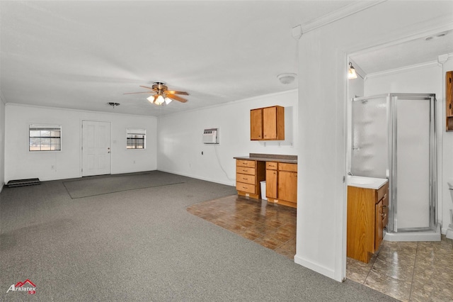 unfurnished living room with dark colored carpet, ornamental molding, and ceiling fan