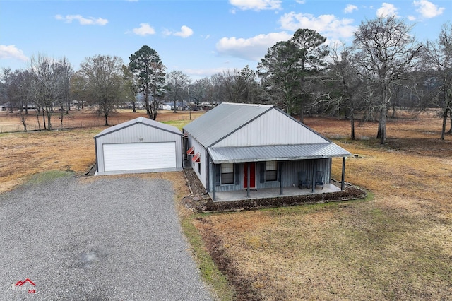 view of front facade featuring a garage, an outbuilding, covered porch, and a front lawn