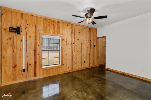 spare room with ceiling fan and wood walls