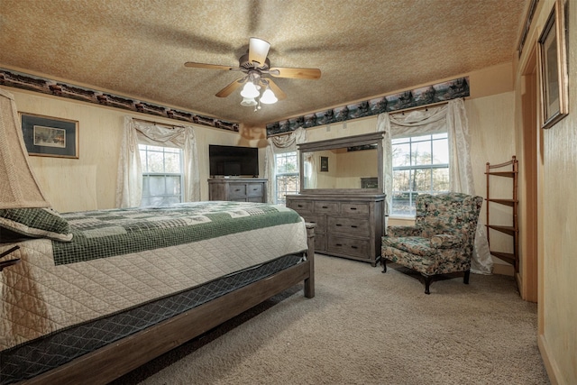 bedroom featuring multiple windows, ceiling fan, light colored carpet, and a textured ceiling