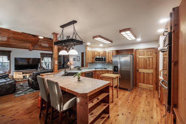 kitchen featuring sink, appliances with stainless steel finishes, tasteful backsplash, tile countertops, and kitchen peninsula