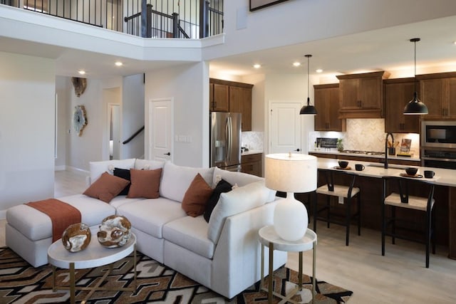 living room with sink, light hardwood / wood-style flooring, and a high ceiling