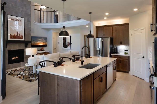 kitchen with sink, light hardwood / wood-style flooring, a center island with sink, stainless steel appliances, and a kitchen bar