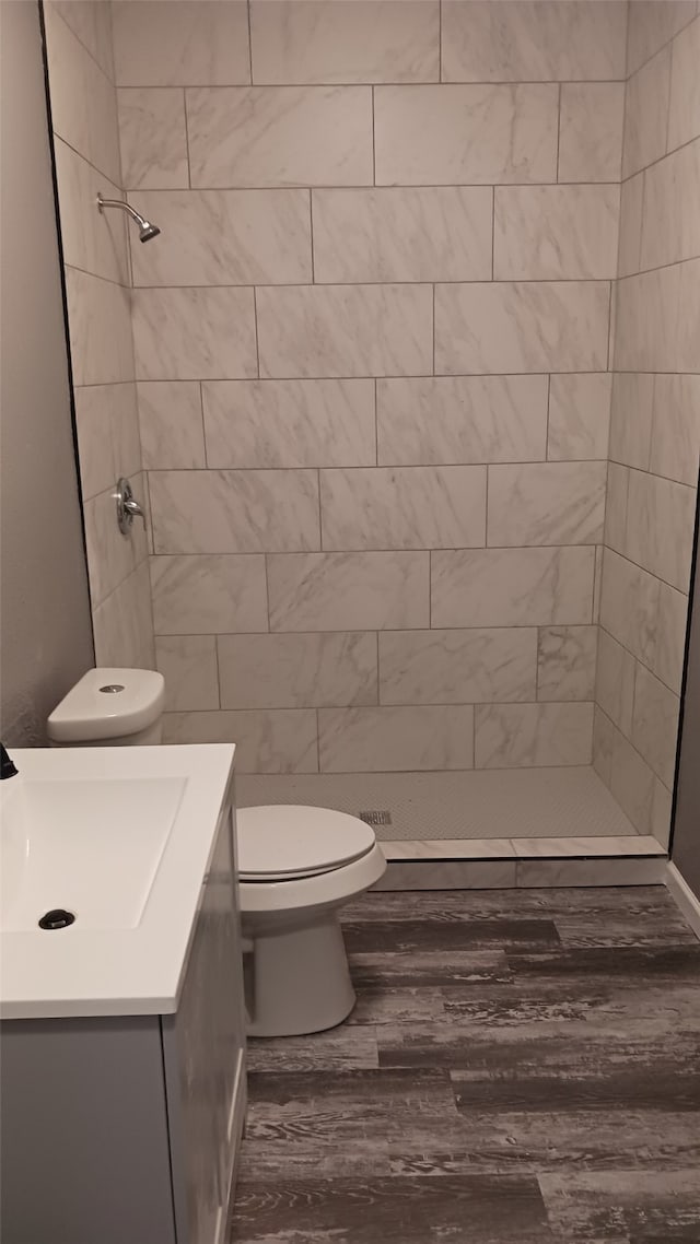 bathroom with vanity, toilet, hardwood / wood-style floors, and a tile shower