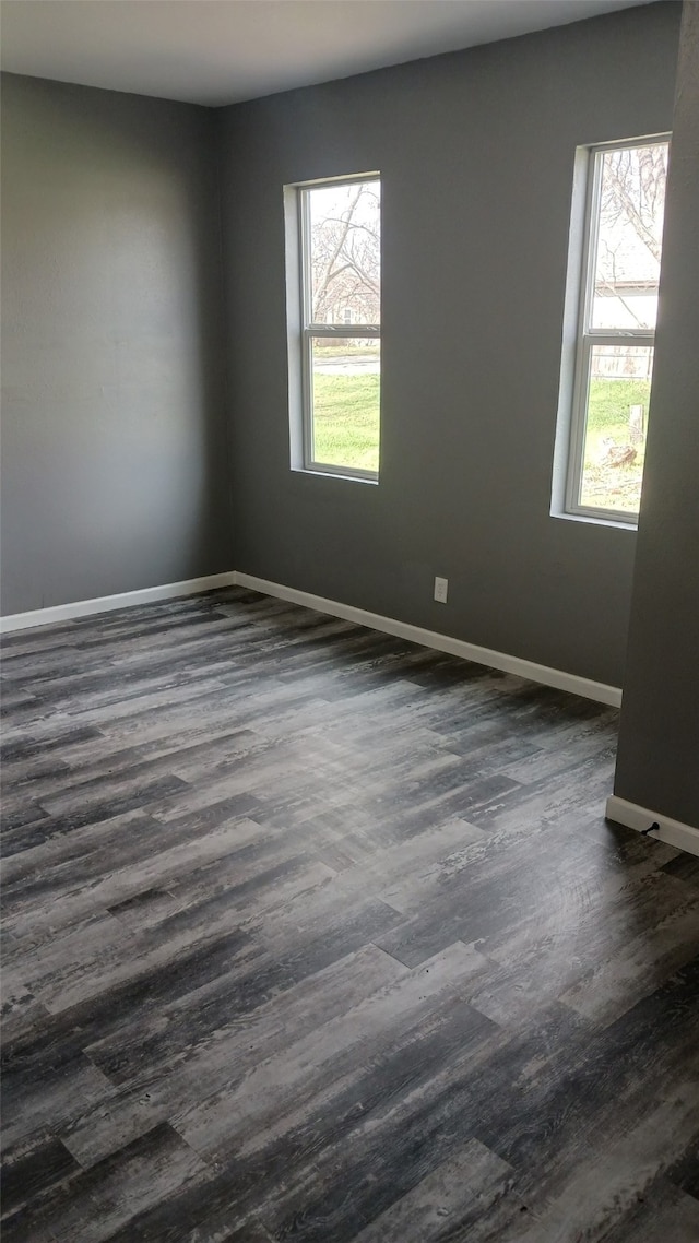 empty room featuring plenty of natural light and dark hardwood / wood-style floors