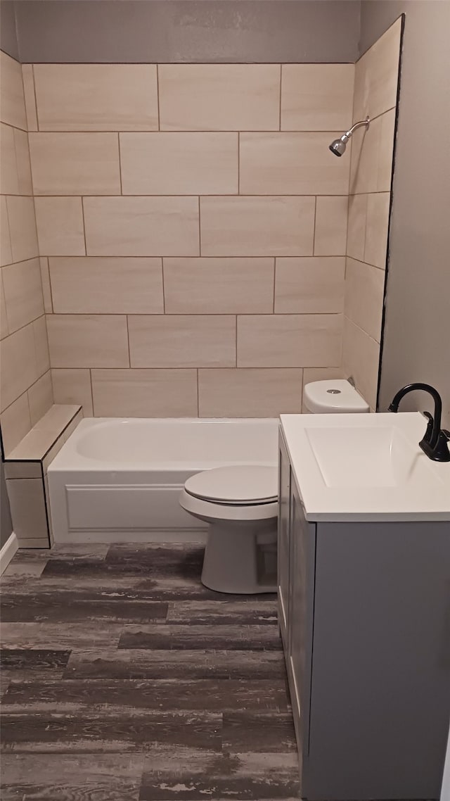 full bathroom with tiled shower / bath combo, vanity, wood-type flooring, and toilet