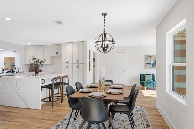 dining room featuring sink, a notable chandelier, and light hardwood / wood-style floors