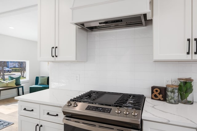 kitchen featuring gas range, white cabinets, extractor fan, and decorative backsplash