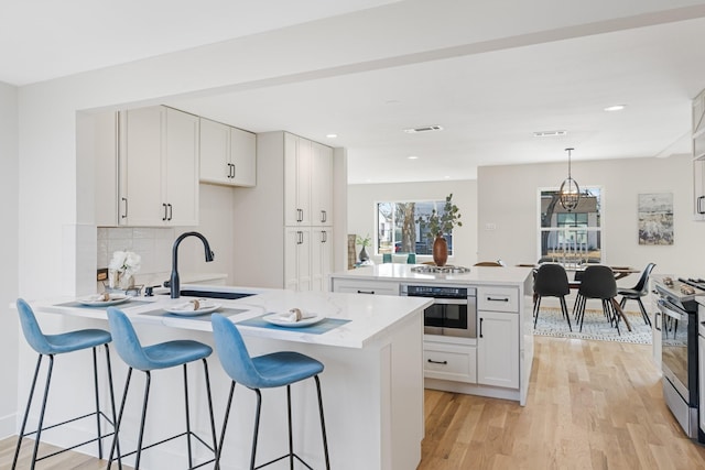 kitchen featuring sink, white cabinetry, stainless steel appliances, decorative light fixtures, and kitchen peninsula