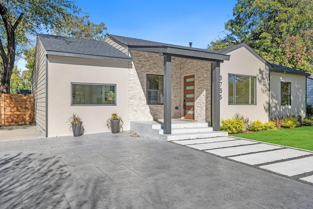 view of front of property with a front yard, fence, stone siding, and stucco siding