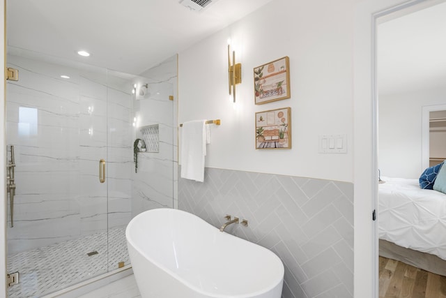 bathroom featuring tile walls, hardwood / wood-style floors, and independent shower and bath