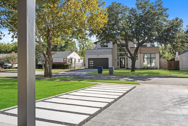 view of front facade featuring a garage, driveway, fence, and a front lawn