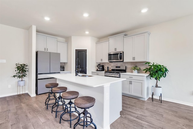 kitchen with a kitchen island with sink, stainless steel appliances, and white cabinets