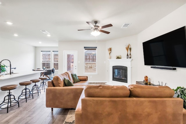 living room with sink, wood-type flooring, ceiling fan, and plenty of natural light