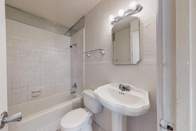 bathroom featuring tile walls, tiled shower / bath combo, toilet, and a textured ceiling