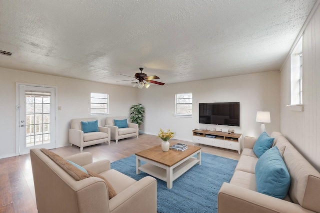 living room featuring ceiling fan, a textured ceiling, and light hardwood / wood-style flooring