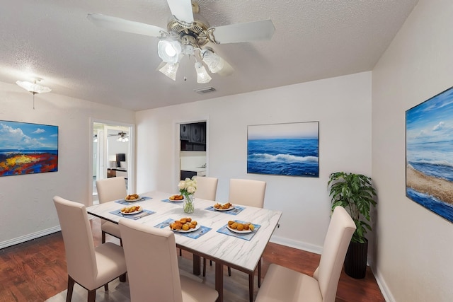 dining area featuring ceiling fan, dark wood-type flooring, and a textured ceiling