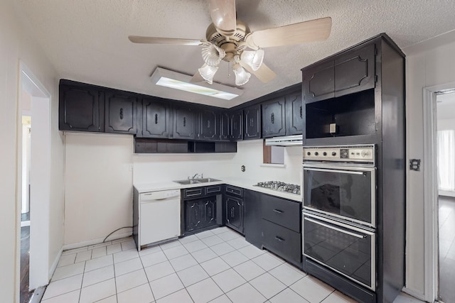 kitchen featuring sink, light tile patterned floors, gas cooktop, white dishwasher, and a textured ceiling