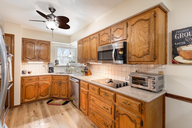 kitchen featuring sink, tasteful backsplash, light wood-type flooring, ceiling fan, and stainless steel appliances