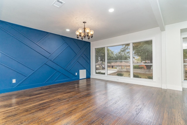 spare room with beamed ceiling, dark hardwood / wood-style floors, and a chandelier