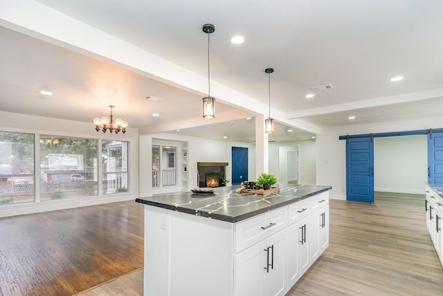 kitchen with white cabinetry, hanging light fixtures, beam ceiling, a kitchen island, and a barn door