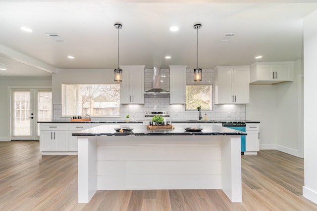 kitchen with white cabinetry, pendant lighting, and wall chimney exhaust hood