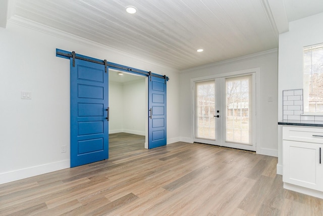 unfurnished room featuring ornamental molding, a barn door, light hardwood / wood-style flooring, and french doors