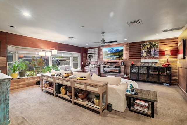 living room featuring wooden walls, light colored carpet, and ceiling fan