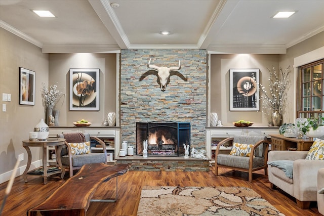 living room with crown molding, a stone fireplace, and wood-type flooring