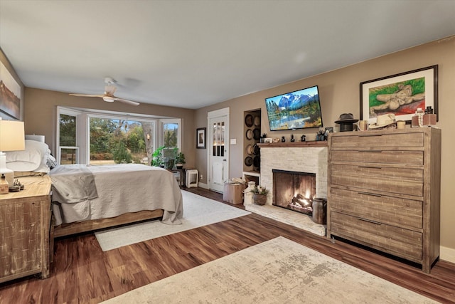 bedroom featuring hardwood / wood-style flooring, a fireplace, and ceiling fan