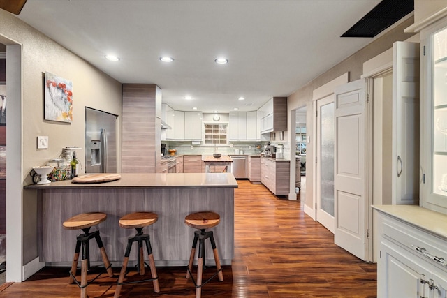 kitchen featuring white cabinetry, appliances with stainless steel finishes, a kitchen breakfast bar, and kitchen peninsula