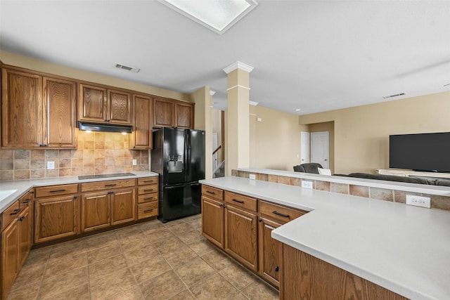 kitchen with ornate columns, kitchen peninsula, decorative backsplash, and black appliances