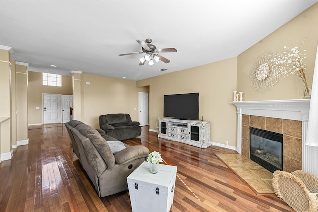 living room featuring dark wood-type flooring, a tile fireplace, and ceiling fan