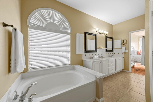 bathroom featuring backsplash, tile patterned flooring, vanity, a healthy amount of sunlight, and a bath