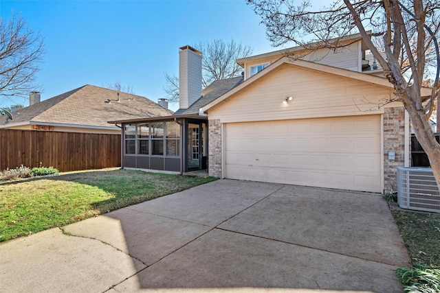 back of property with a garage, a sunroom, a yard, and central air condition unit