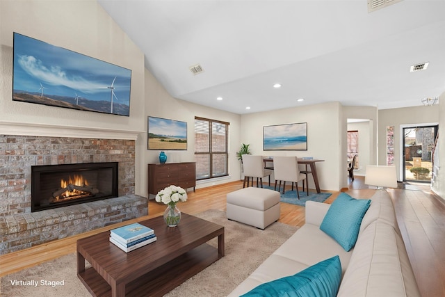 living room with lofted ceiling, a fireplace, and light hardwood / wood-style flooring