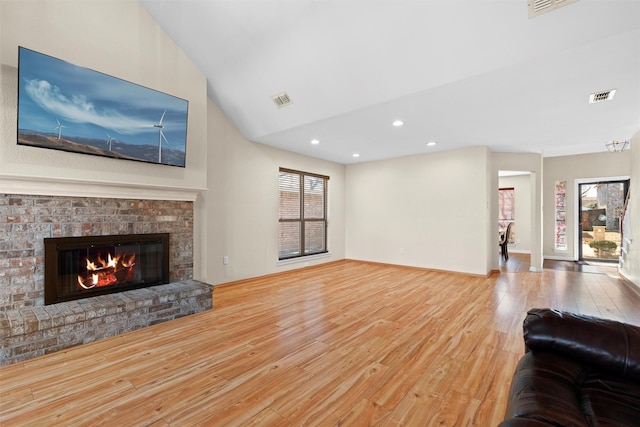 living room with lofted ceiling, a fireplace, and light hardwood / wood-style flooring