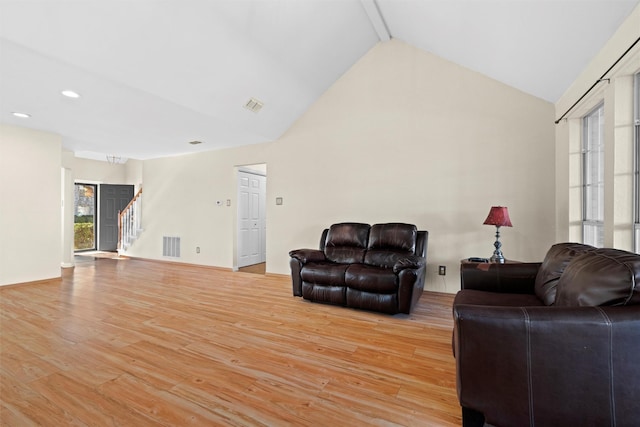 living room featuring light hardwood / wood-style flooring, high vaulted ceiling, and beamed ceiling