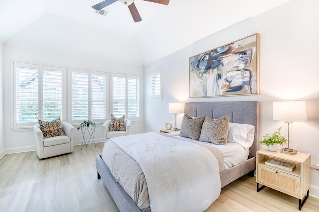 bedroom with lofted ceiling, a tray ceiling, light hardwood / wood-style flooring, and ceiling fan