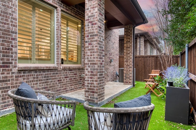 patio terrace at dusk featuring a lawn