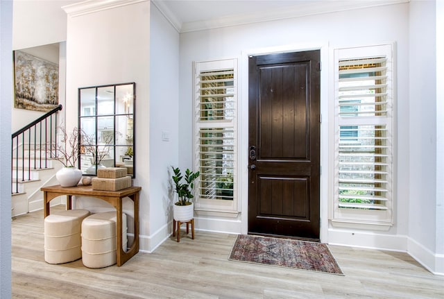 foyer featuring crown molding, light hardwood / wood-style flooring, and a healthy amount of sunlight