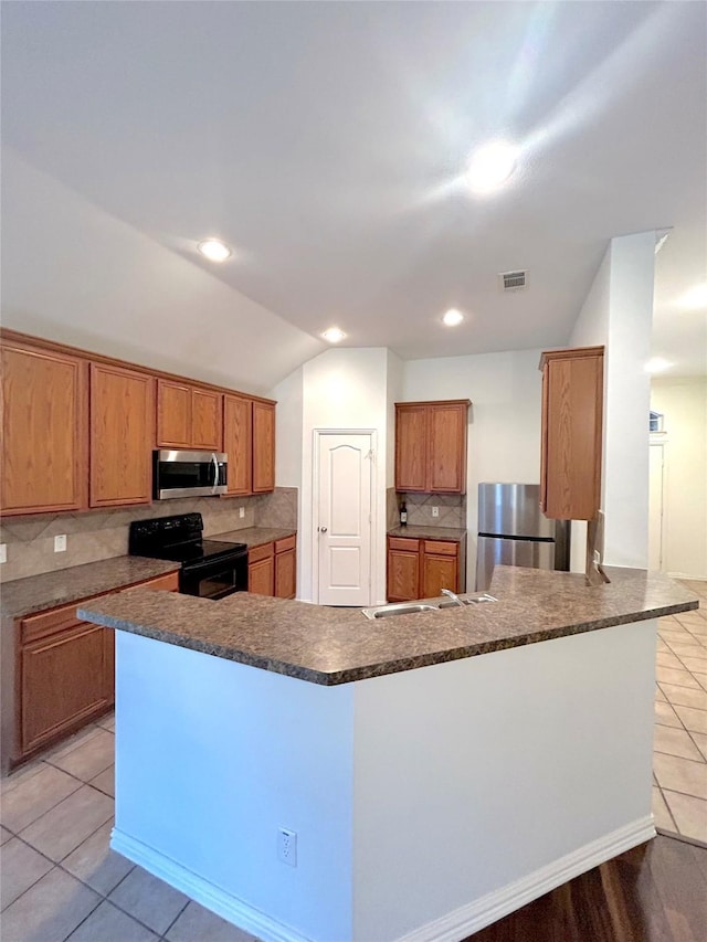 kitchen with vaulted ceiling, light tile patterned flooring, appliances with stainless steel finishes, backsplash, and kitchen peninsula