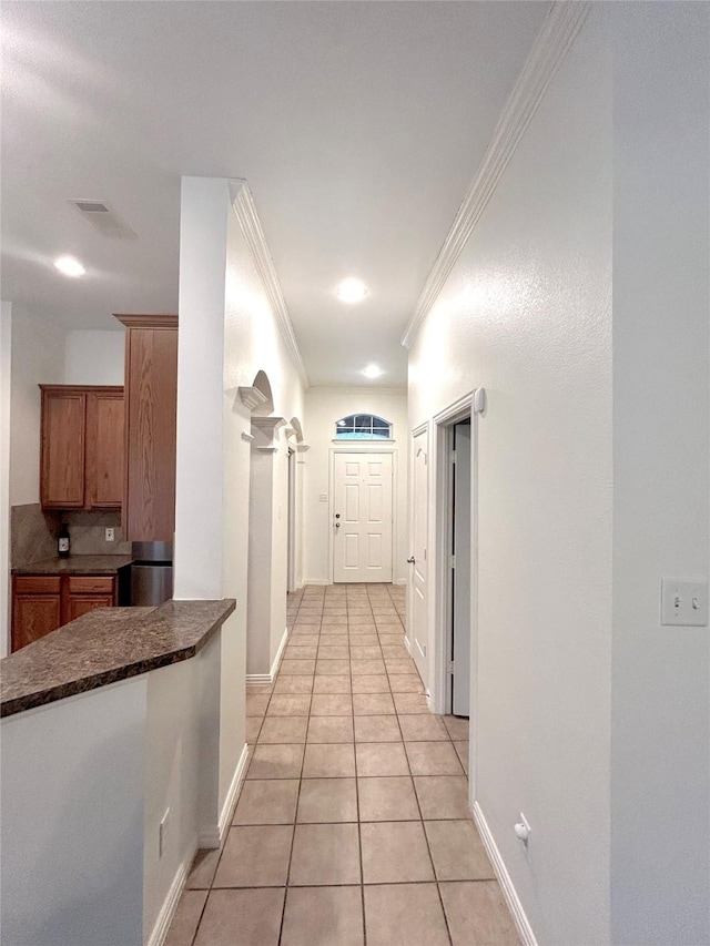 corridor featuring light tile patterned floors and crown molding